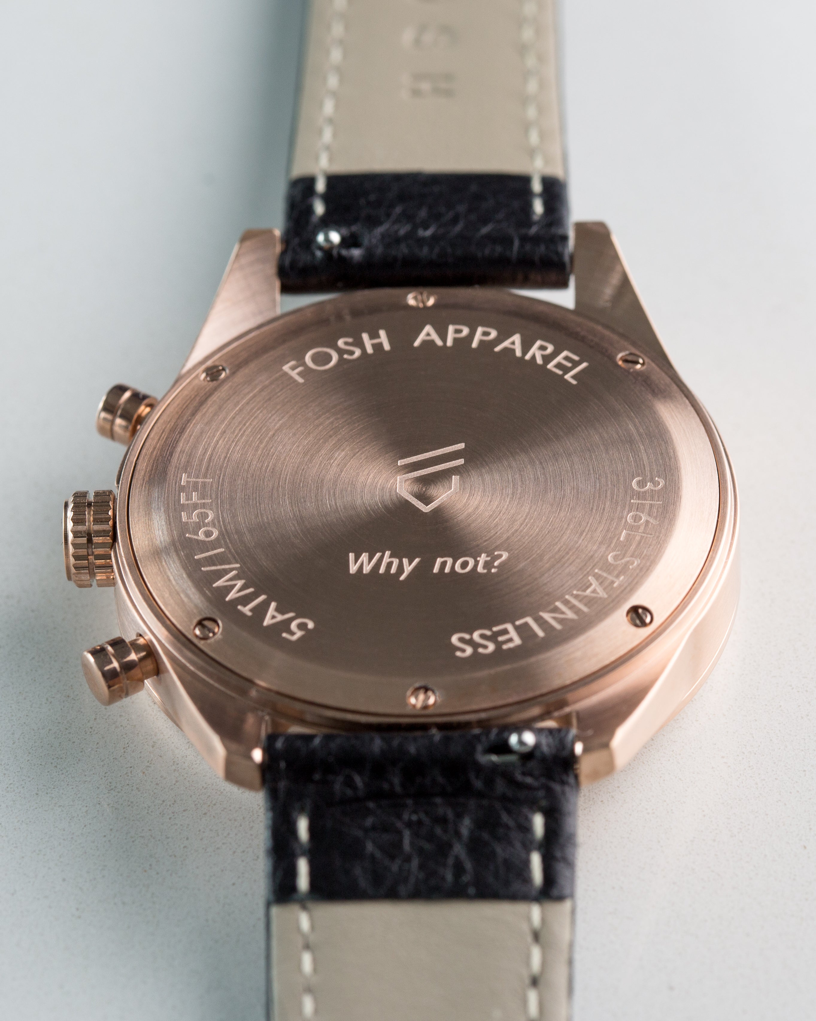 Back of rose gold watch case with engraved logo reading "why not"