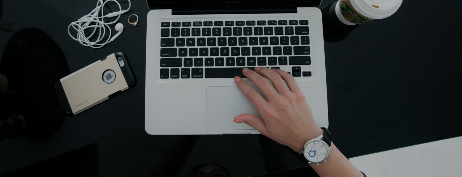 women hand typing on computer wearing white face and blue second hand chronograph watch with coffee and cell phone   